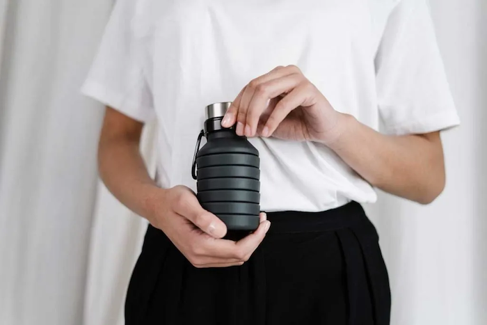 holding a reusable water bottle insead of using single use plastic water bottles copy