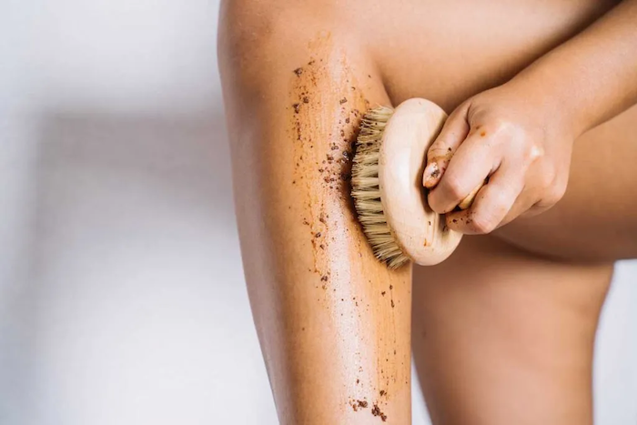 woman exfoliating her skin using the dry brush technique copy