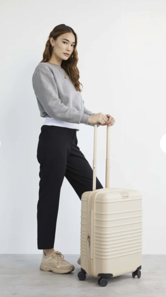 woman standing beside beis travel best carry-on luggage for women.png